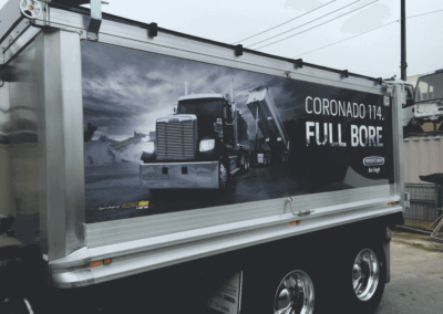 A tandem tipper's trailer has a large format black and white (photo) digital sign applied to both sides